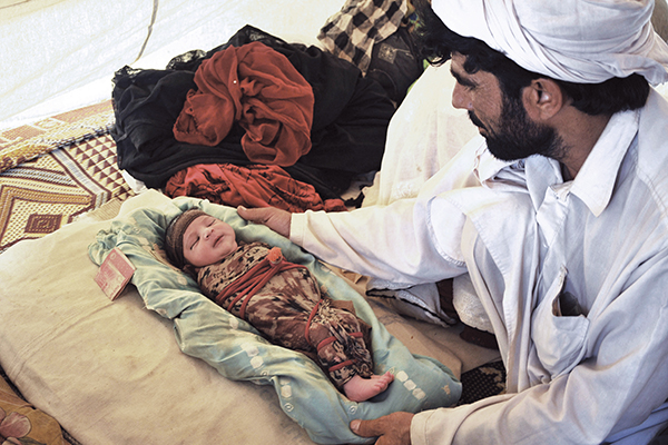 Azb, born at Bakkakhel camp on June 28, with his father. Hasham Ahmed—AFP