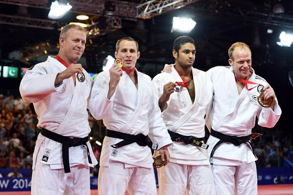 Shah Hussain (2nd right) displays his silver medal at the Commonwealth Games. Carl Court—AFP