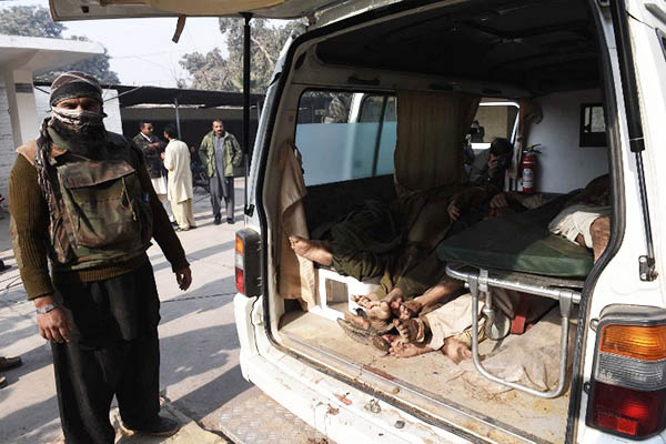 A security official stands next to bodies of suspected Taliban militants. A. Majeed—AFP