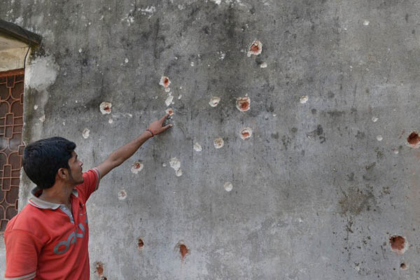 A Pakistani points to bullet holes in the wall of his home, allegedly caused by Indian firing, near Sialkot. Arif Ali—AFP