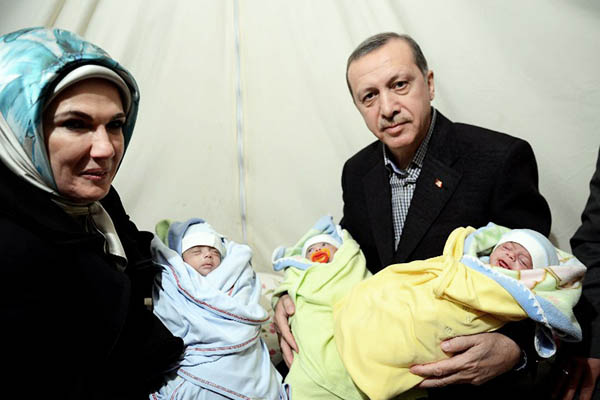 Turkish Prime Minister Recep Tayyip Erdogan and his wife Emine Erdogan hold babies during a visit to the Akcakale Refugee camp, 2012. AFP