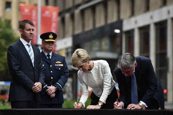 British Foreign Secretary Philip Hammond (right) and Australian Foreign Minister Julie Bishop sign a condolence book for victims of a siege at the Lindt Cafe in Sydney. Peter Parks—AFP