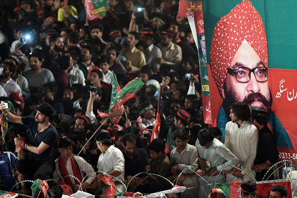 PTI activists gather in front of a poster featuring Sardar Soran Singh. Farooq Naeem—AFP