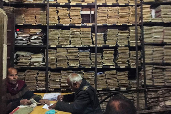 Indian government employees work next to stacks of files at the office of the registrar in the district court of Allahabad. Chandan Khanna—AFP