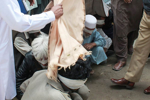 Police cover members of the accused jirga as they arrive at a court in Abbottabad. Shakeel Ahmed—AFP